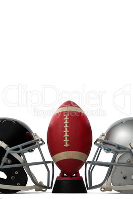 American football on tee by silver and black sports helmets