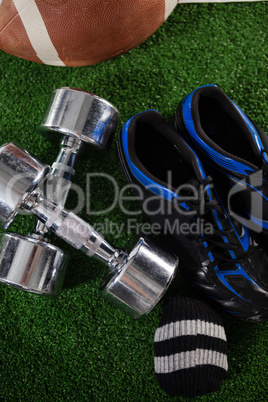 High angle view of dumbbells by sports shoe and American football