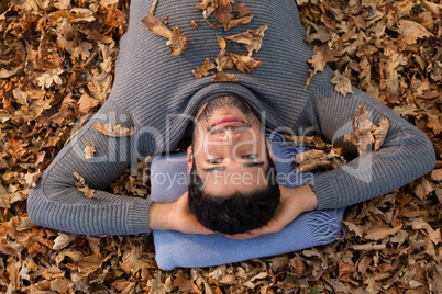 Overhead of man lying on autumn leaves