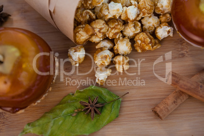 Popcorn, apple and spices on wooden table