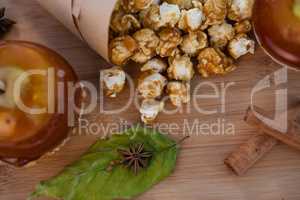 Popcorn, apple and spices on wooden table