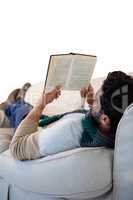 Man lying on sofa while reading book