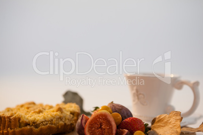Autumn leaves, various fruits and cup of tea on chopping board