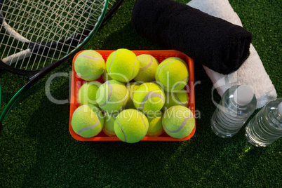Overhead view of tennis balls in container amidst rackets and napkins by water bottles