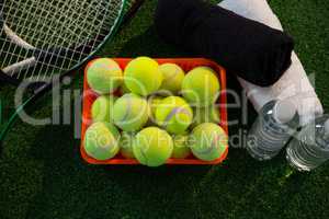Overhead view of tennis balls in container amidst rackets and napkins by water bottles
