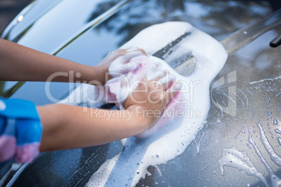 Teenage girl washing a car