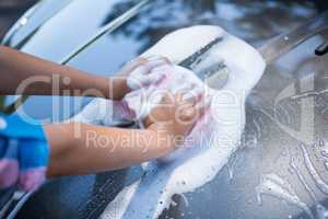 Teenage girl washing a car