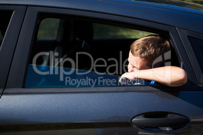 Teenage boy looking from open car window