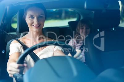 Woman driving a car while daughter sitting in the backseat of car