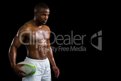 Aggressive shirtless athlete holding rugby ball