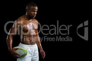 Aggressive shirtless athlete holding rugby ball
