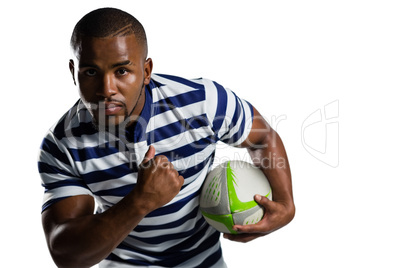 Young sportsman with ball running while playing rugby