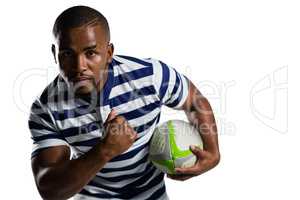 Young sportsman with ball running while playing rugby
