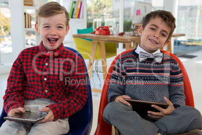 Kids as business executives holding digital tablet while sitting