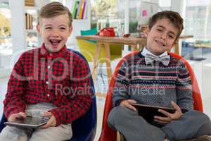 Kids as business executives holding digital tablet while sitting