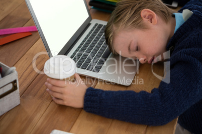 Boy as business executive sleeping while holding coffee cup