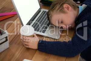 Boy as business executive sleeping while holding coffee cup