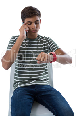 Teenage boy talking on smartphone looking at his smartwatch
