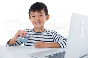 Boy using laptop and credit card against white background