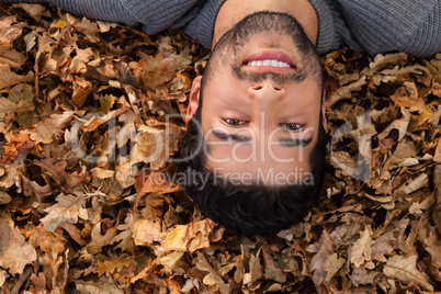 Overhead of man lying on autumn leaves