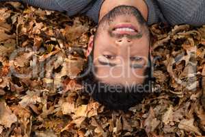 Overhead of man lying on autumn leaves