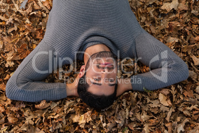 Overhead of man lying on autumn leaves