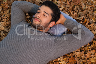 Overhead of man lying on autumn leaves