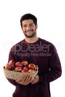 Portrait of smiling man holding basket of apples