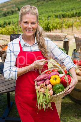 Happy woman holding a basket of fresh vegetables at stall
