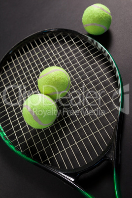 High angle view of fluorescent yellow tennis balls and racket