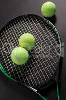 High angle view of fluorescent yellow tennis balls and racket
