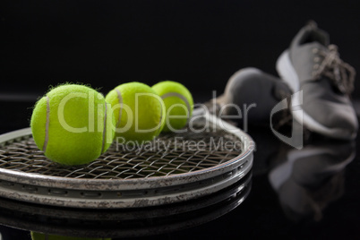 Close up of fluorescent yellow tennis balls on racket by sports shoes
