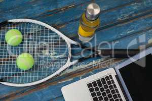 High angle view of laptop by tennis racket and balls with water bottle