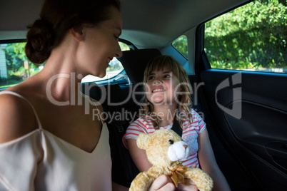 Mother and daughter sitting in the back seat of car