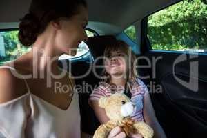 Mother and daughter sitting in the back seat of car