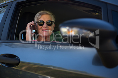 Senior woman talking on mobile phone in car