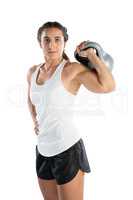 Portrait of female athlete holding kettlebell standing with hand on hip