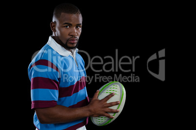 Portrait of confident male player holding rugby ball