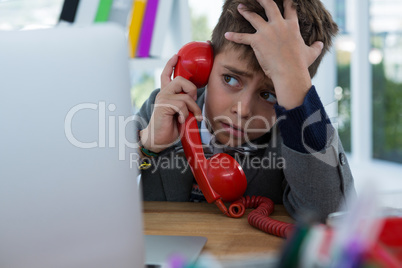 Boy as business executive talking on phone