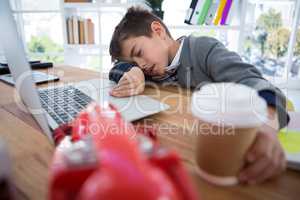 Boy as business executive sleeping while holding coffee cup