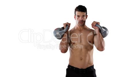 Portrait of shirtless sports player exercising with kettle bells