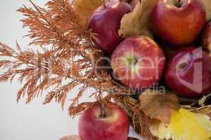 Close-up of red apples with autumn leaves in wicker basket