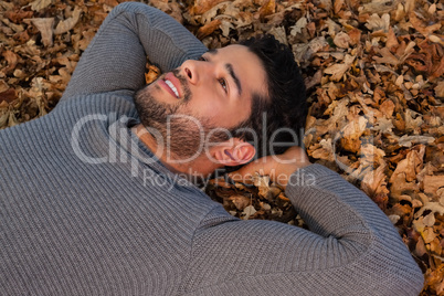 Overhead of man lying on autumn leaves