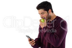 Man eating apple while using mobile phone
