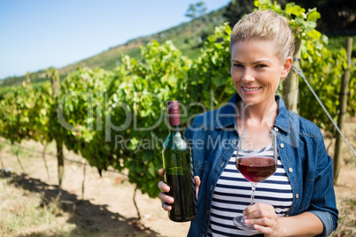 Portrait of female vintner examining wine in vineyard