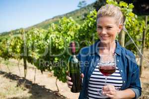 Portrait of female vintner examining wine in vineyard