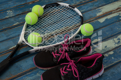 High angle view of black sports shoes by tennis balls and racket