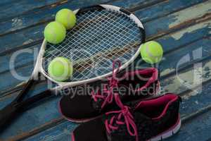 High angle view of black sports shoes by tennis balls and racket