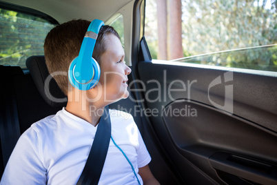 Teenage boy with headphones sitting in the back seat of car