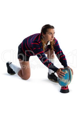 Side view of female athlete keeping rugby ball on tee